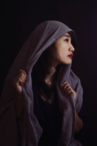 Close-up of young woman against black background