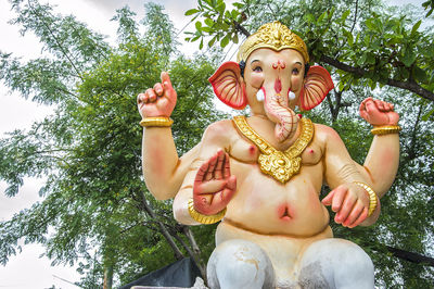 Low angle view of ganesha statue against trees