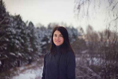 Portrait of woman standing against trees during winter