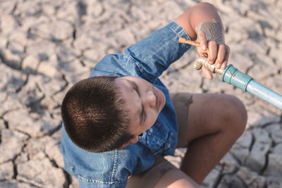 Boy looking at faucet during summer