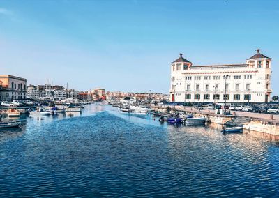 Sailboats in city against clear blue sky