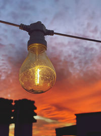 Low angle view of illuminated light bulb against sky