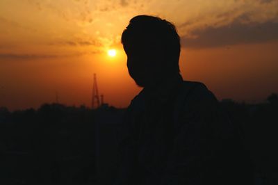 Silhouette of man photographing at sunset