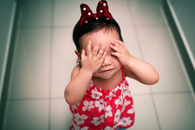 Girl covering eyes with hands on floor