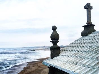 View of cross on beach against sky