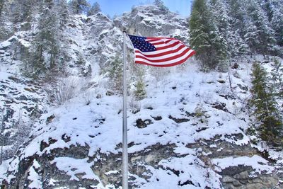 American flag waving against snow covered mountain