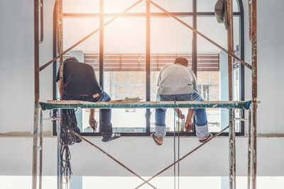 Rear view of men sitting on railing