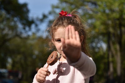 Close-up of girl eating ice cream against sky