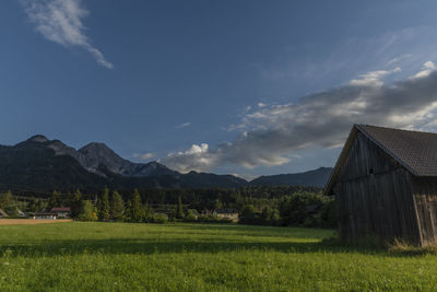 Scenic view of field by mountains against sky