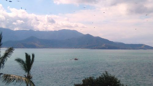 Scenic view of sea and mountains against sky