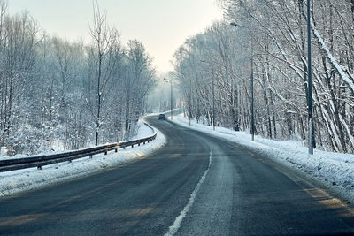 Empty road along snow covered trees