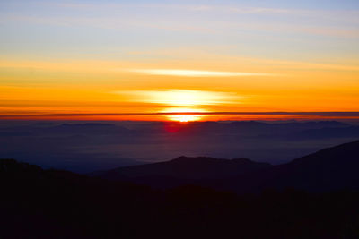 Scenic view of silhouette mountains against orange sky