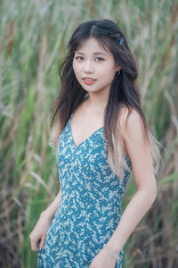 Portrait of young woman standing against plants