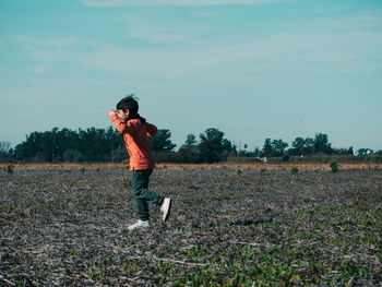 Full length of boy standing on field against sky