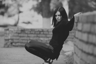 Portrait of woman crouching against wall