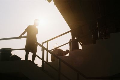 Low angle view of silhouette people standing on staircase against sky