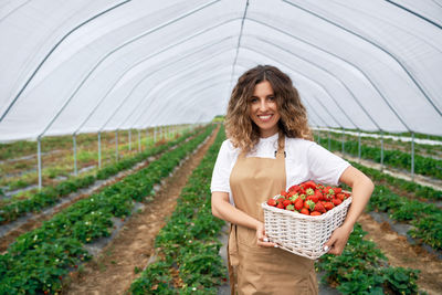 Smiling young woman holding ice cream in greenhouse