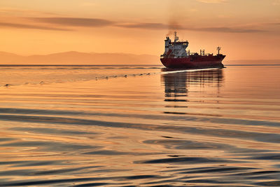 Ship in sea against sky during sunset