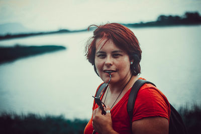 Portrait of smiling young woman against lake