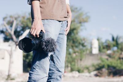 Midsection of man holding camera