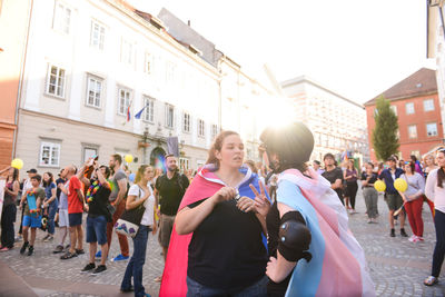 People holding smart phone in city against sky