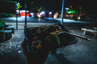 Close-up of hand holding ice cream cone at night