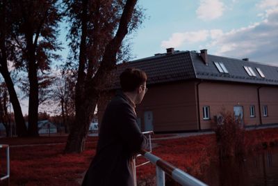 Side view of young woman standing against trees