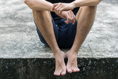 Low section of man sitting on footpath