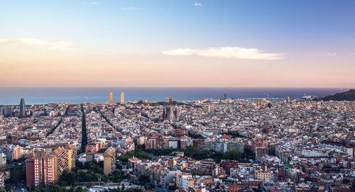 High angle view of illuminated cityscape by sea against sky