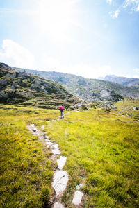 Rear view of woman walking on mountain against cloudy sky