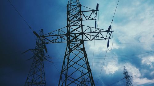 Low angle view of electricity pylon against blue sky