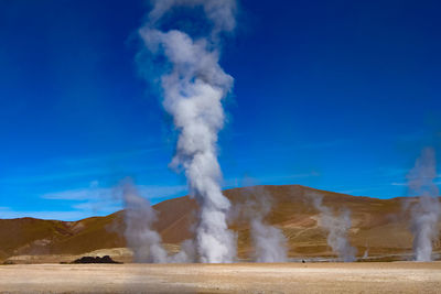 Smoke emitting from volcanic land against sky