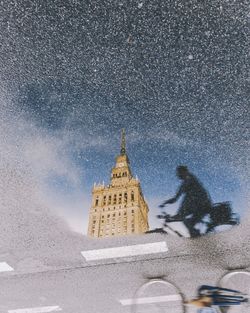 Reflection of building and man on puddle at street