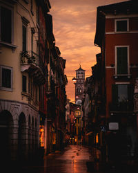 Street amidst buildings against sky during sunset