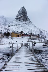 Snow covered mountain by buildings against sky