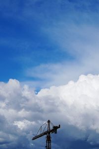 Low angle view of crane against cloudy sky