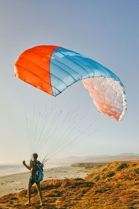Young man paragliding during sunset off cliffs in baja, mexico.