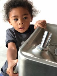 Cute boy playing with drinking fountain at home