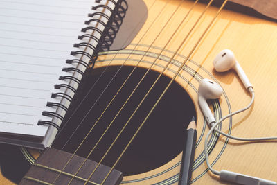 High angle view of book and headphones on guitar