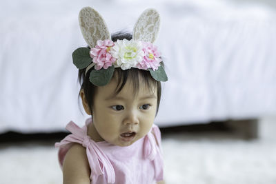 Close-up cute baby girl wearing headband sitting at home