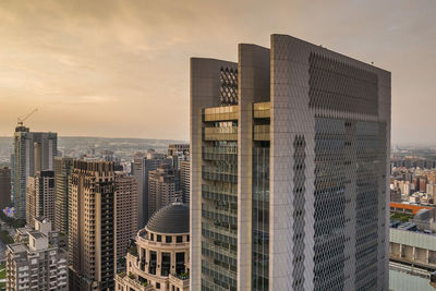 Modern buildings in city against sky during sunset