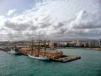 Boats in harbor against cloudy sky