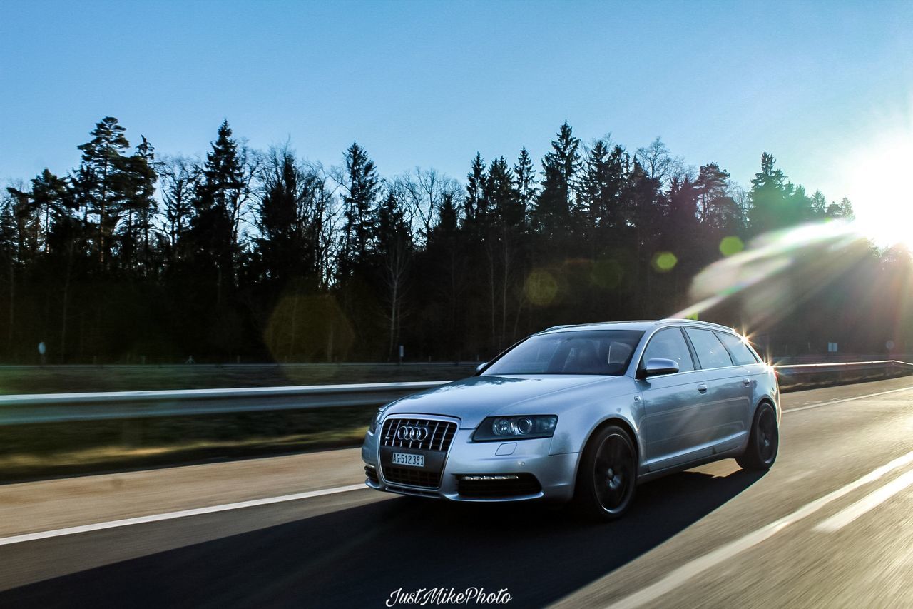 car, mode of transportation, tree, motor vehicle, transportation, plant, land vehicle, nature, sunlight, road, sky, no people, day, speed, motion, blurred motion, blue, growth, travel, clear sky, outdoors, road trip