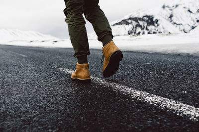 Low section of man walking on road during winter