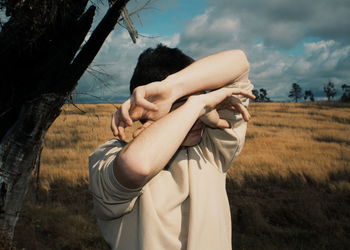 Midsection of woman standing on field against sky