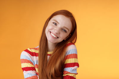 Smiling woman with head cocked against yellow background