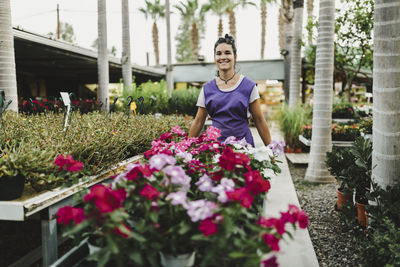 Smiling female entrepreneur with flowering plants at garden center