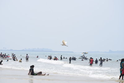 People on beach against clear sky