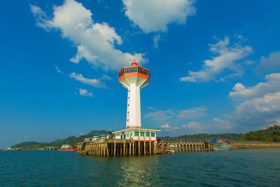 View of tower in sea against cloudy sky