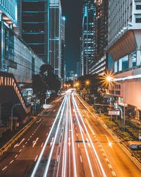 Light trails on road amidst buildings in city at night